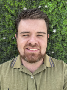 Picture of John Capps, PhD in a green shirt with a green grassy background